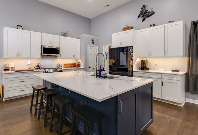 a kitchen with a sink a stove a refrigerator and white cabinets with wooden floor