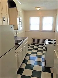 a kitchen with a checkered floor and white cabinets