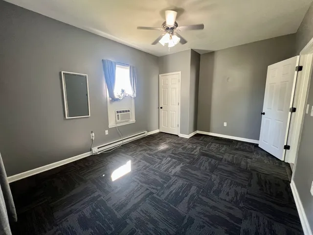 a view of an empty room with window and wooden floor