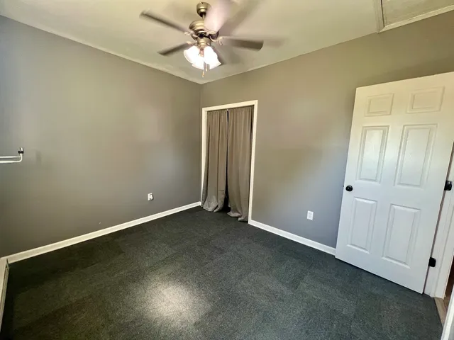 an empty room with closet and a ceiling fan