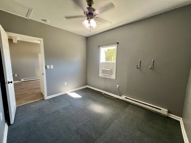 an empty room with windows and fan