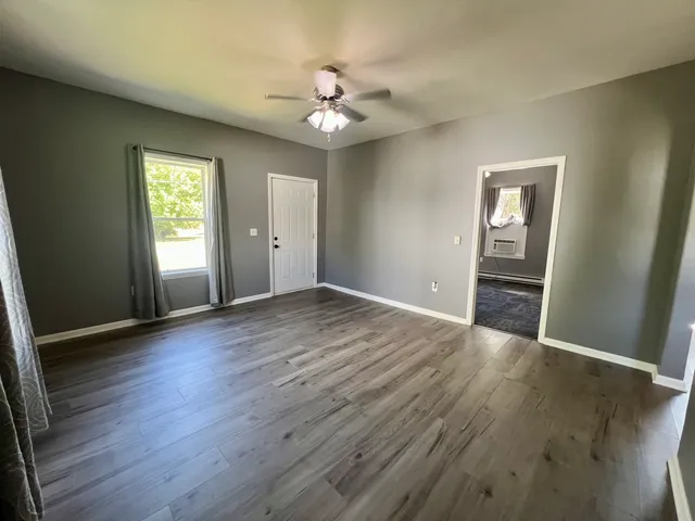 a view of an empty room with wooden floor and a window