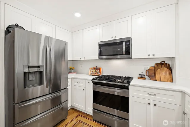 a kitchen with stainless steel appliances white cabinets and a stove a refrigerator with wooden floor