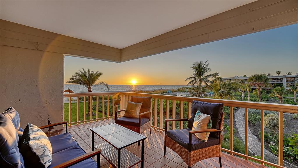 5757 Gulf Of Mexico Drive, Unit 204 Longboat Key, FL 34228 - Photo 14 of 71 a balcony with wooden floor and outdoor seating