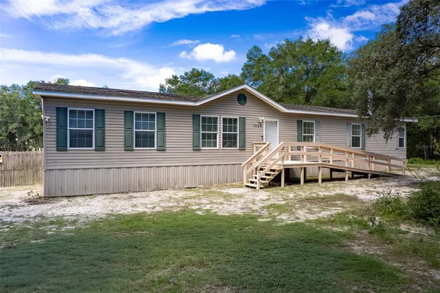 a view of a house with a big yard and large tree