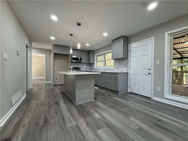 a kitchen with stainless steel appliances granite countertop a sink a stove a refrigerator cabinets and a wooden floor