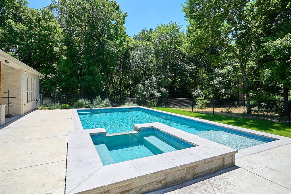 358 Glade Valley Road Azle, TX 76020 - Photo 30 of 35 Outdoor living space featuring a rectangular swimming pool with an integrated spa, extensive concrete patio, and a stone-clad raised pool surround