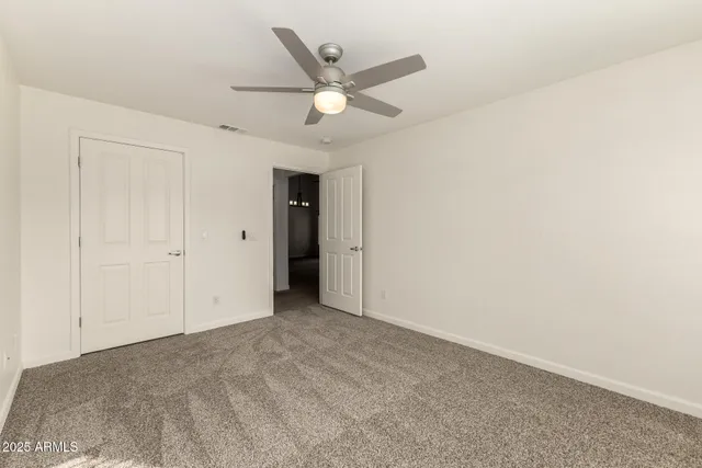 an empty room with closet and ceiling fan