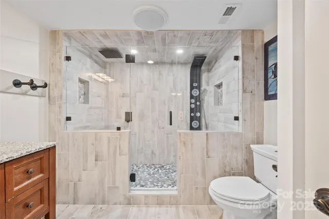 a bathroom with a granite countertop sink a toilet a shower and a mirror