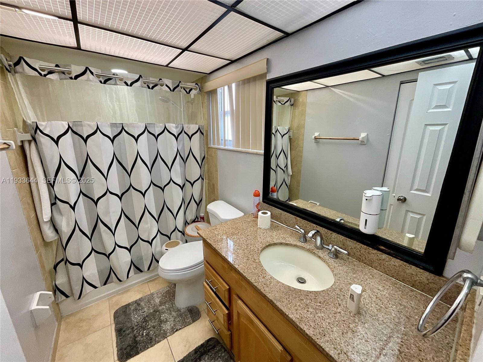 1750 West 46th Street, Unit 544 Hialeah, FL 33012 - Photo 25 of 44 a bathroom with a granite countertop sink toilet and a mirror
