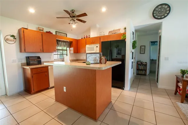 a kitchen with kitchen island granite countertop a sink a counter top space appliances and cabinets
