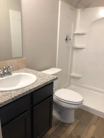 a bathroom with a granite countertop toilet sink and a mirror