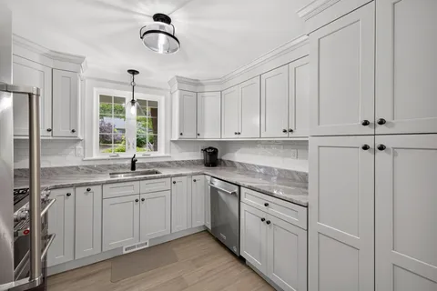 a kitchen with white cabinets and sink
