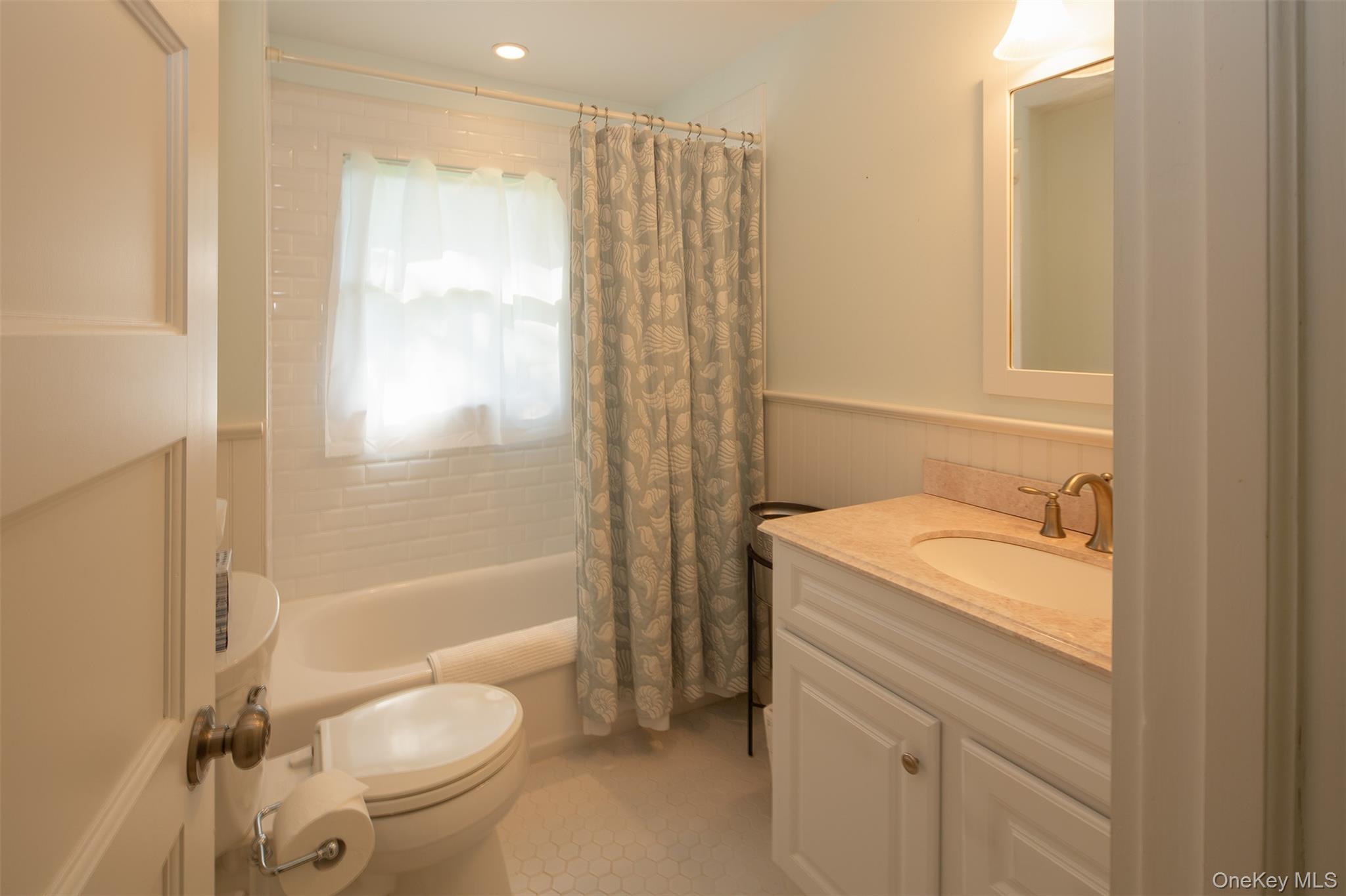1 Canal Road Hampton Bays, NY 11946 - Photo 26 of 50 Bathroom featuring shower / bathtub combination with curtain, vanity, a wainscoted wall, and light tile patterned floors