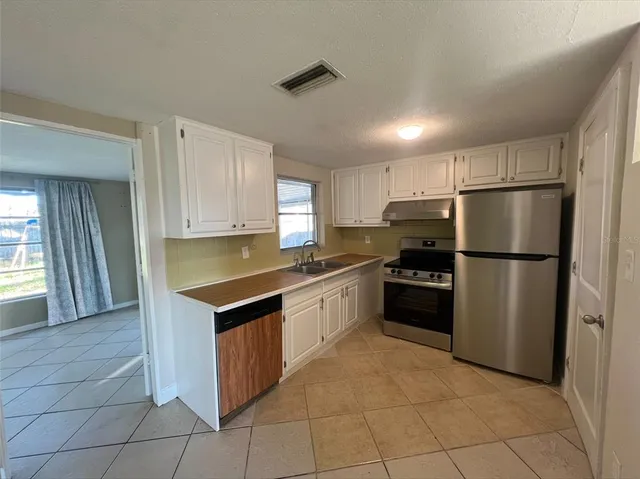 a kitchen with granite countertop a refrigerator and a stove top oven