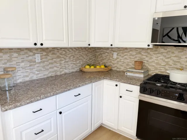 a kitchen with granite countertop white cabinets and white appliances