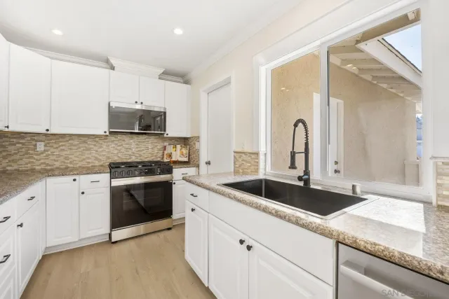 a kitchen with stainless steel appliances granite countertop a sink and white cabinets