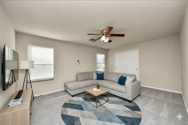a living room with furniture a ceiling fan and a window
