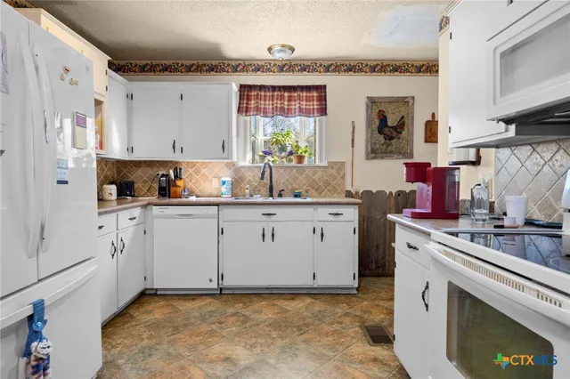 a kitchen with granite countertop white cabinets and white appliances