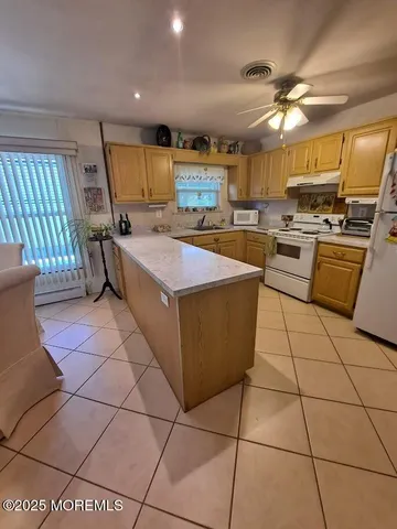 a large kitchen with kitchen island a stove a sink a counter top space and cabinets
