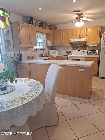 a kitchen with stainless steel appliances granite countertop a sink a stove a dining table and chairs