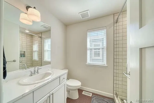 a bathroom with a toilet a sink a mirror a window and vanity