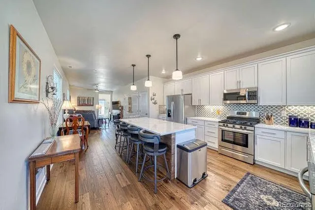 a open kitchen with stainless steel appliances granite countertop a stove and refrigerator a oven with wooden floors