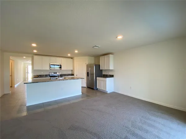 a view of kitchen with kitchen island white cabinets and refrigerator