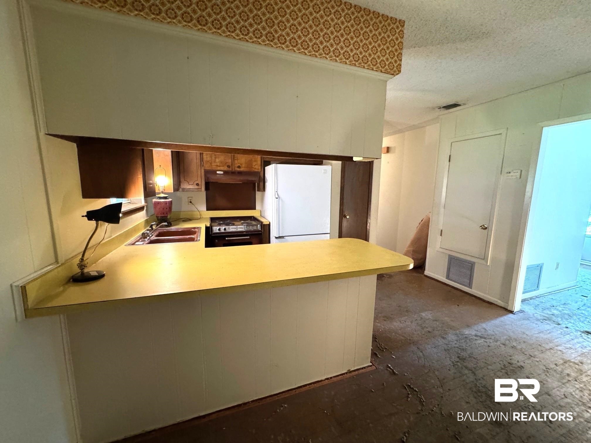 5198 Lancelot Drive Mobile, AL 36619 - Photo 7 of 30 Kitchen with freestanding refrigerator, light countertops, a peninsula, a textured ceiling, and stove