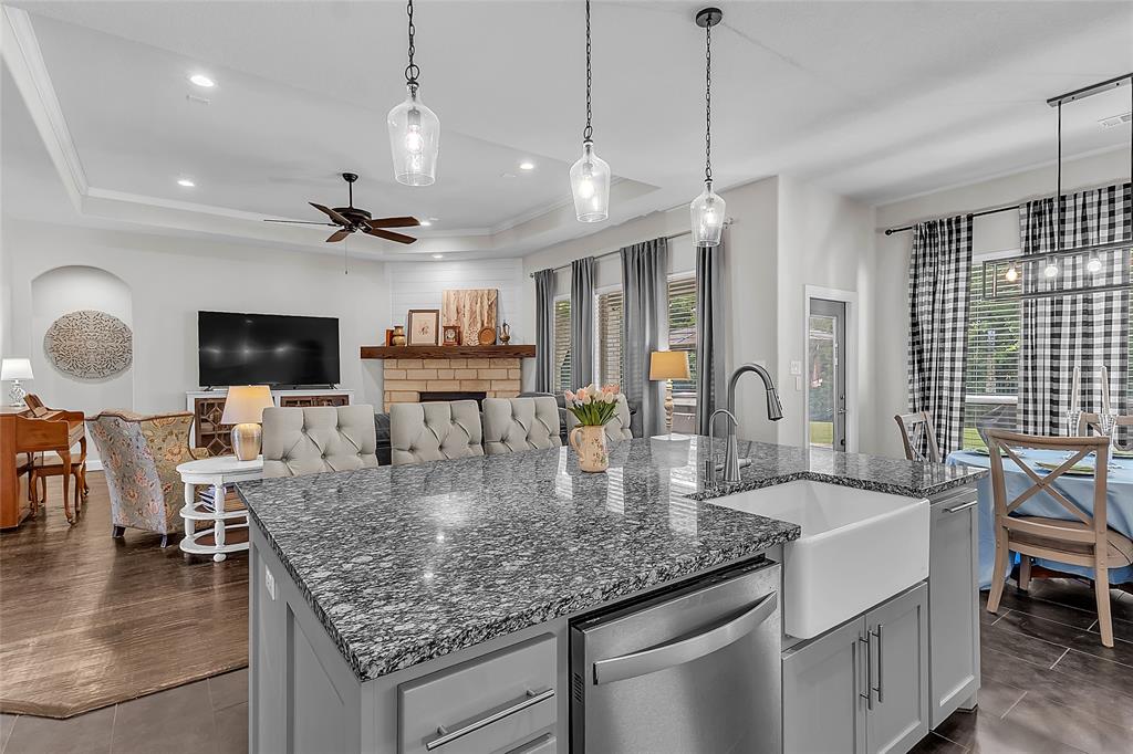 1014 Rennard Street Caddo Mills, TX 75135 - Photo 10 of 39 Kitchen featuring a large island with a granite countertop, shaker-style cabinetry with ample storage, integrated stainless steel appliances, and dark tile flooring overlooking main living and dining areas and back door