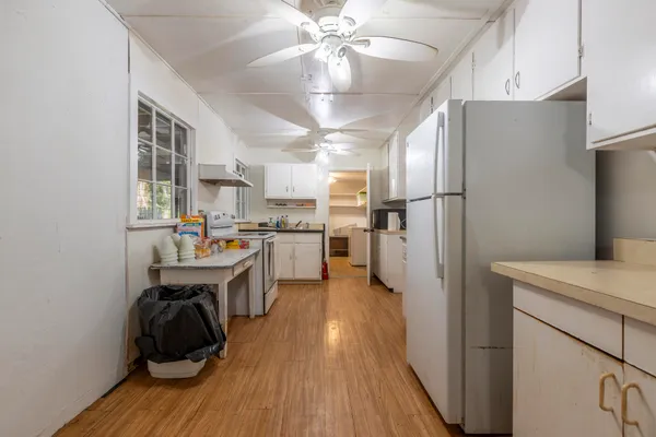 a kitchen with refrigerator a sink dishwasher a dining table and chairs with wooden floor