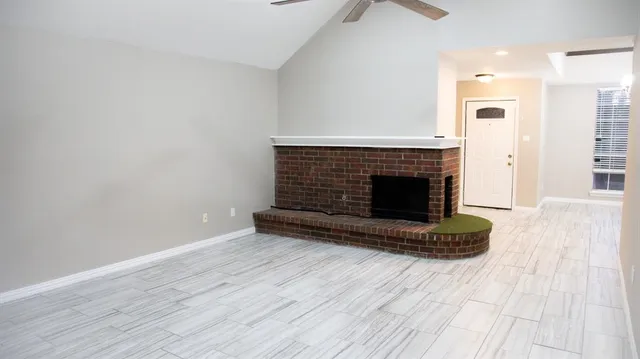 an empty room with wooden floor fireplace and windows