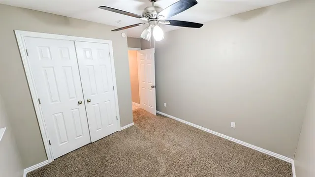 an empty room with a ceiling fan and a window