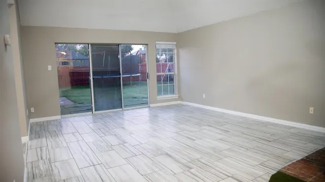 a view of an empty room with wooden floor and a fireplace