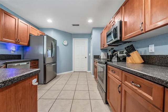 a kitchen with stainless steel appliances granite countertop a refrigerator a stove and a sink