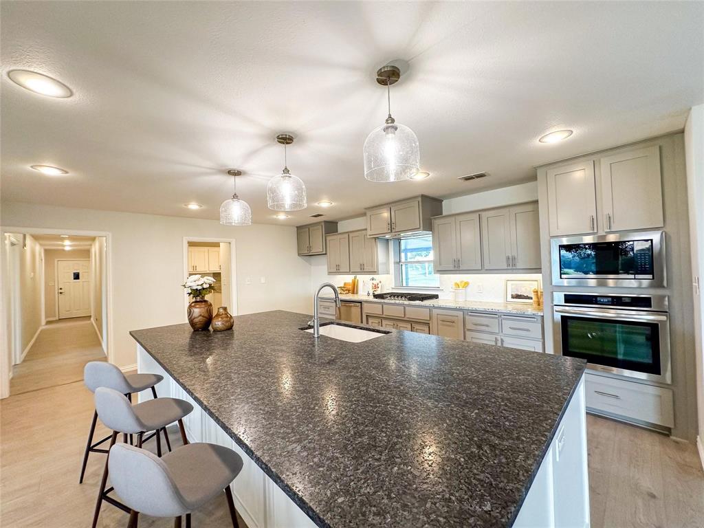 3952 Tin Top Road Weatherford, TX 76087 - Photo 3 of 39 a kitchen with stainless steel appliances granite countertop a stove top oven a sink counter space and living room view