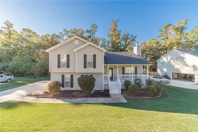 a view of a house with a big yard potted plants and large tree