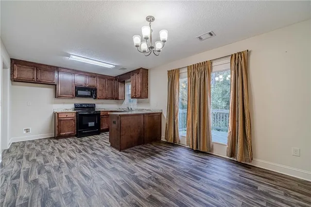 a kitchen with stainless steel appliances granite countertop a refrigerator a stove top oven a sink with wooden floors and cabinets