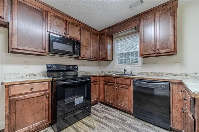 a kitchen with granite countertop stainless steel appliances wooden cabinets and a stove top oven