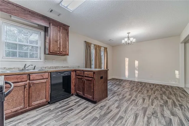 a kitchen with stainless steel appliances granite countertop a stove a sink dishwasher and a refrigerator with wooden floor