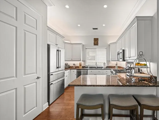 a kitchen with granite countertop white cabinets and stainless steel appliances