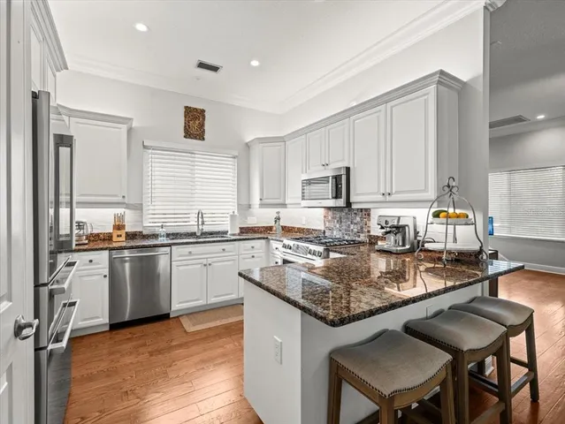 a kitchen with stainless steel appliances granite countertop a stove top oven a sink dishwasher and cabinets with wooden floor