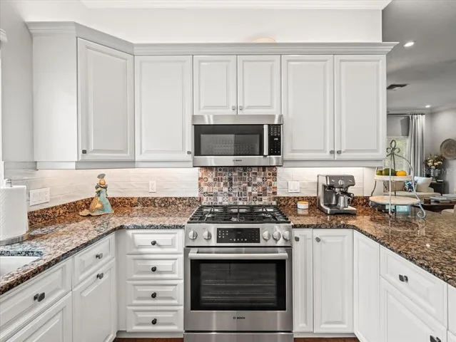 a kitchen with granite countertop white cabinets and stainless steel appliances