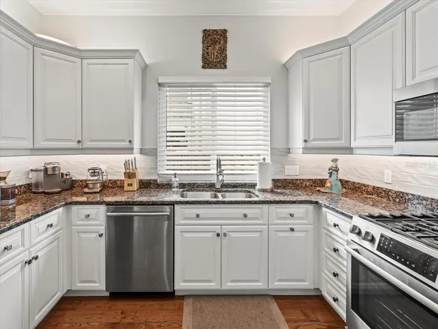 a kitchen with granite countertop cabinets stainless steel appliances and a sink