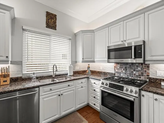 a kitchen with granite countertop cabinets stainless steel appliances a sink and a window