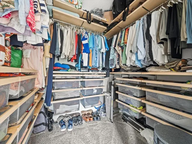 a view of walk in closet with clothes and shoes