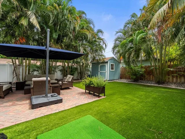 a view of a patio with table and chairs potted plants and large tree