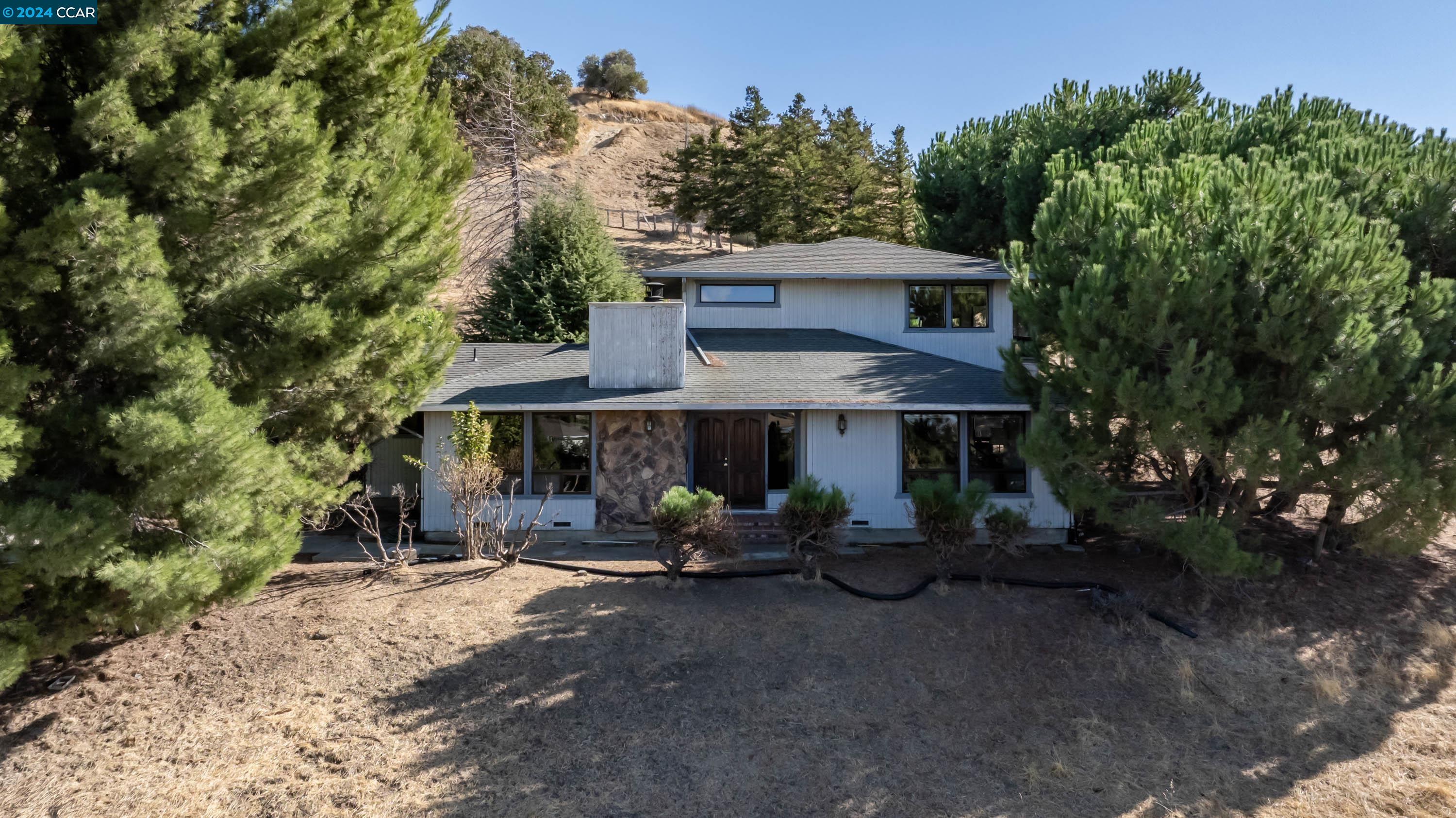 a view of a patio with table and chairs under an umbrella with large trees