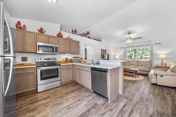 a kitchen with granite countertop wooden floors stainless steel appliances and sink