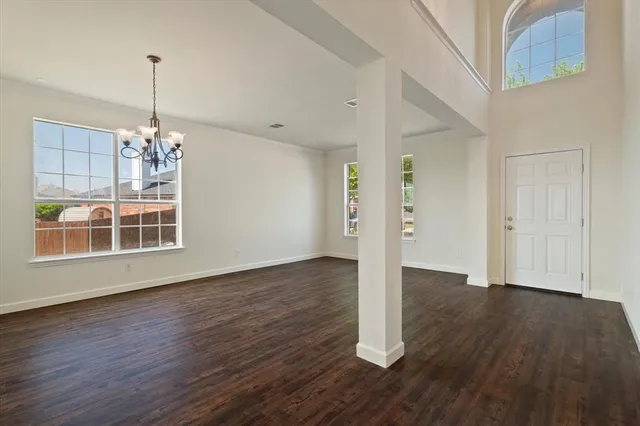 a view of a room with wooden floor chandelier and windows